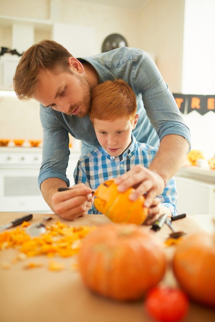 Father carving pumpkin with son