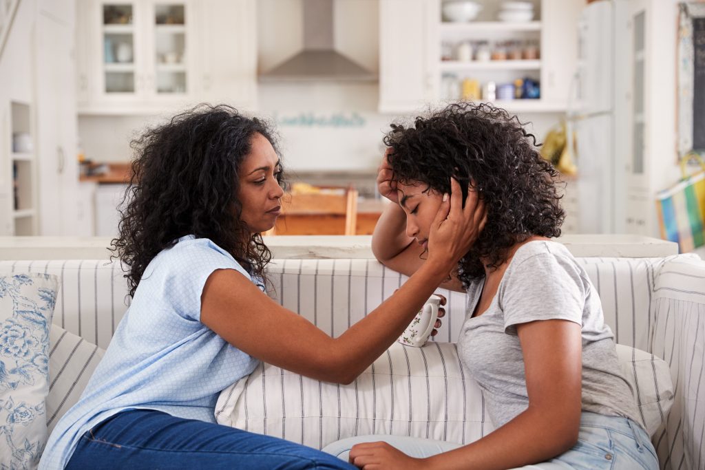 Mother Talking With Unhappy Teenage Daughter On Sofa