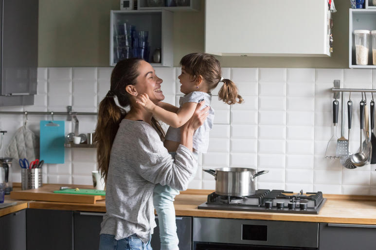 happy mom and daughter playing in kitchen