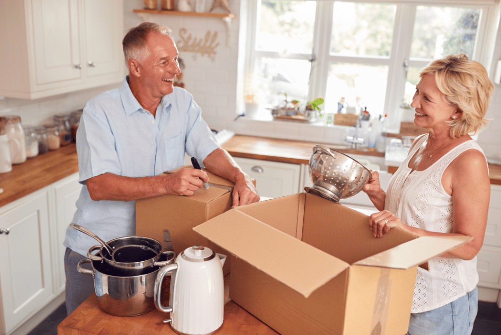 man and woman pack kitchen items into a moving box