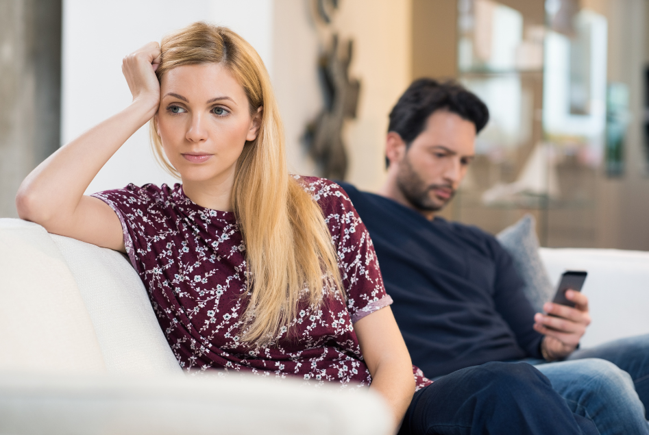 Couple sitting apart on a couch after the holidays, reflecting increasing divorce considerations in January.